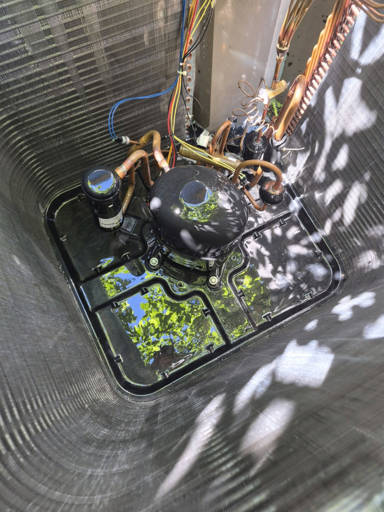 Inside view of condenser with compressor and copper lines